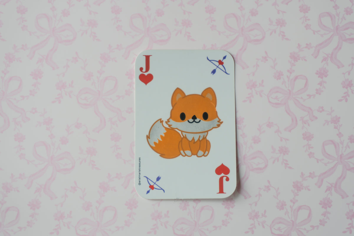 A Jack of Hearts playing card featuring a cute orange fox illustration in the center, displayed on a light pink patterned background.