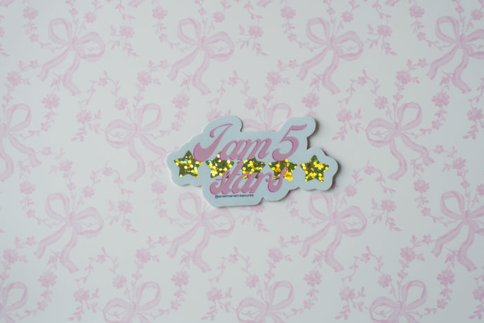 A die-cut sticker featuring the text 'I am 5 stars' in pink cursive with five yellow glittery stars, shown on a light pink floral and bow patterned background.