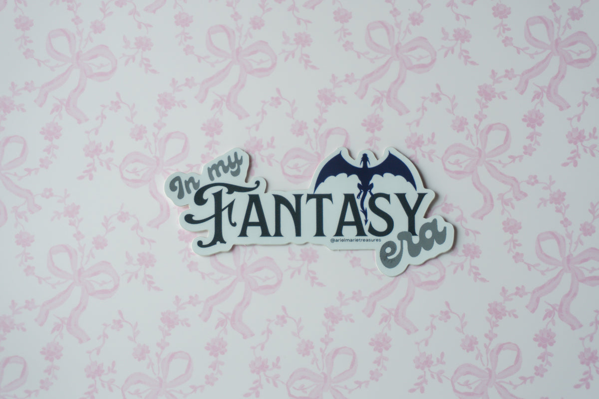 A die-cut sticker with the text 'In my FANTASY era' and a bat silhouette, shown on a white background with a light pink bow pattern.