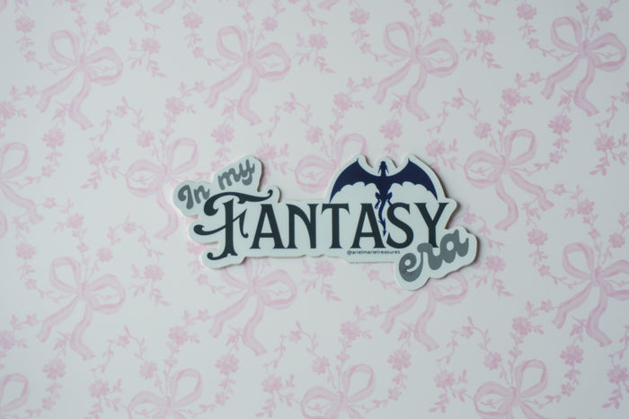 A die-cut sticker with the text 'In my FANTASY era' and a bat silhouette, shown on a white background with a light pink bow pattern.