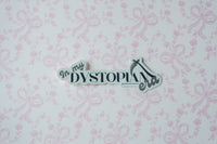 A die-cut sticker with the text 'In my DYSTOPIA era' in black script and serif fonts, featuring a high-heel shoe icon, displayed on a light pink and white patterned background.
