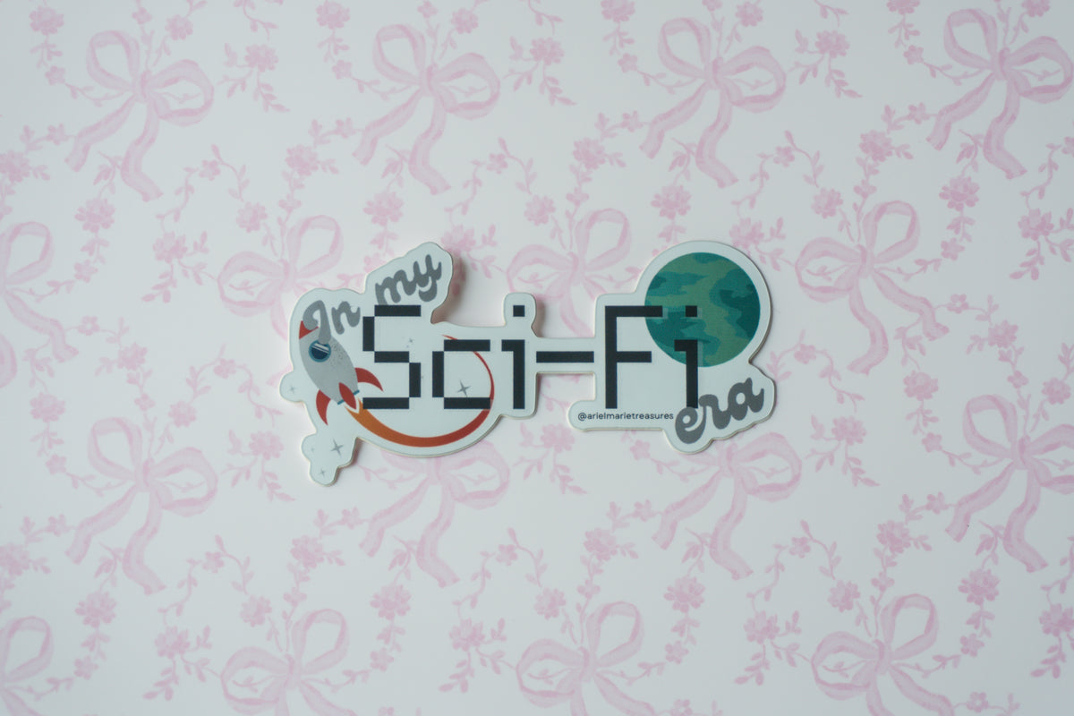 A die-cut sticker with the text 'In my Sci-Fi era' and space-themed illustrations, placed on a light pink floral bow patterned background.