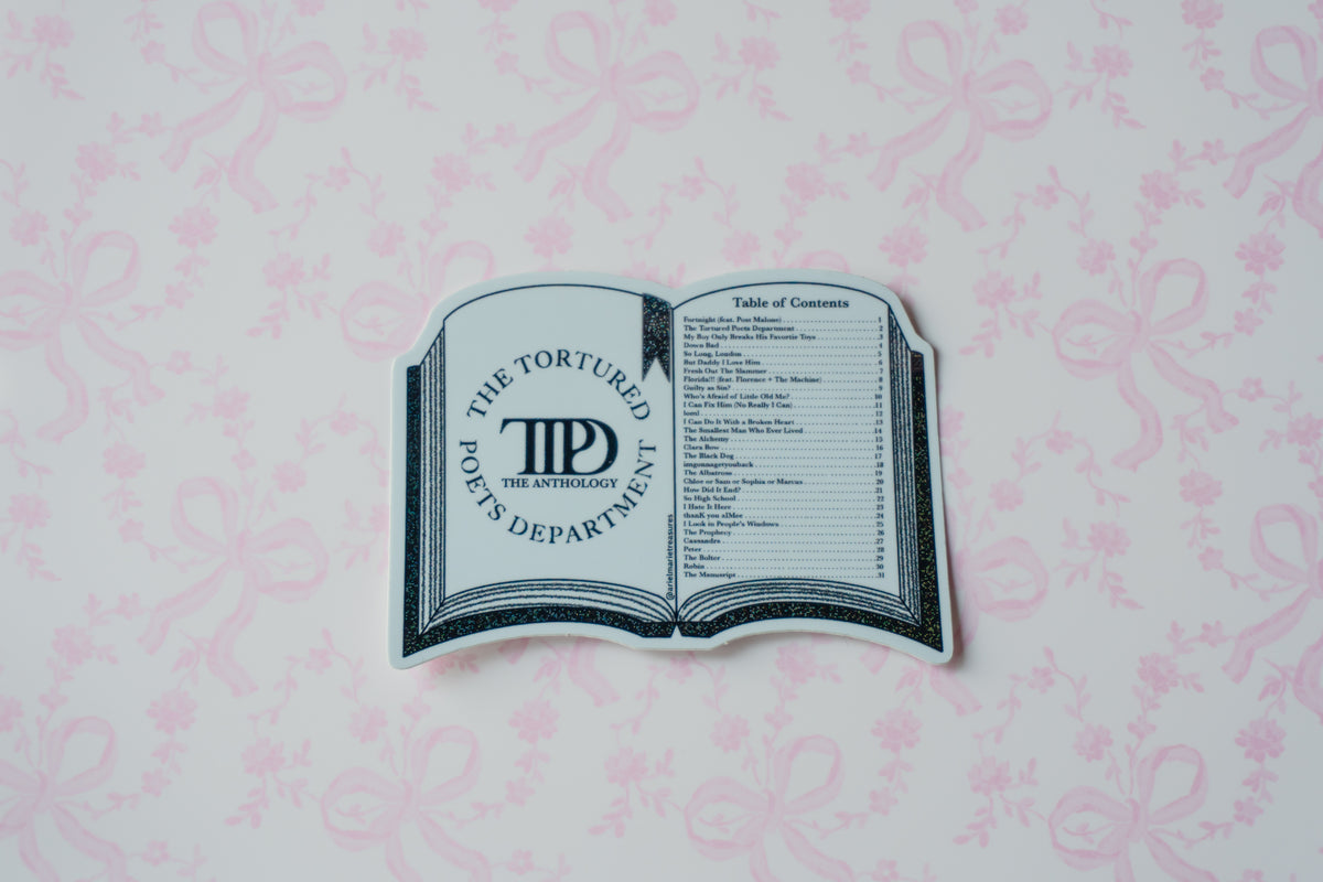 A novelty book-shaped sticker or decal featuring 'The Tortured Poets Department' logo and a table of contents design, placed on a light pink patterned background.