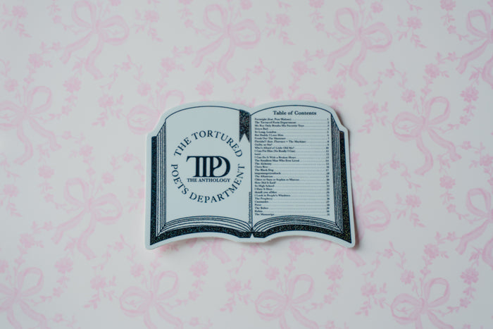 A novelty book-shaped sticker or decal featuring 'The Tortured Poets Department' logo and a table of contents design, placed on a light pink patterned background.