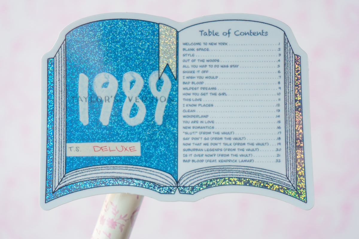 A glittery open-book-shaped sticker or decal featuring the text '1984 T.S.