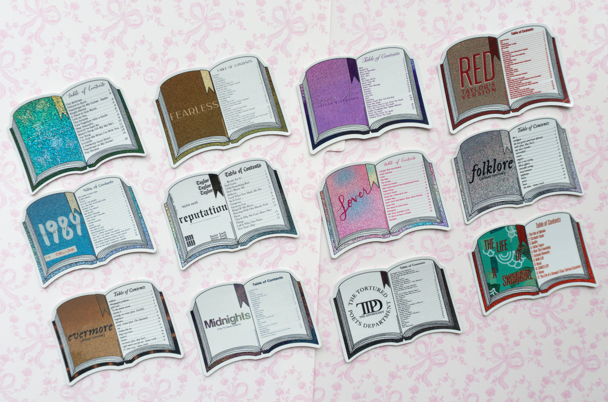 Twelve book-shaped stickers arranged in a grid on a pale pink patterned background. Each sticker depicts an open book with different illustrated covers and titles, including 'RED', '1987', 'reputation', 'folklore', 'Midnights', and others.