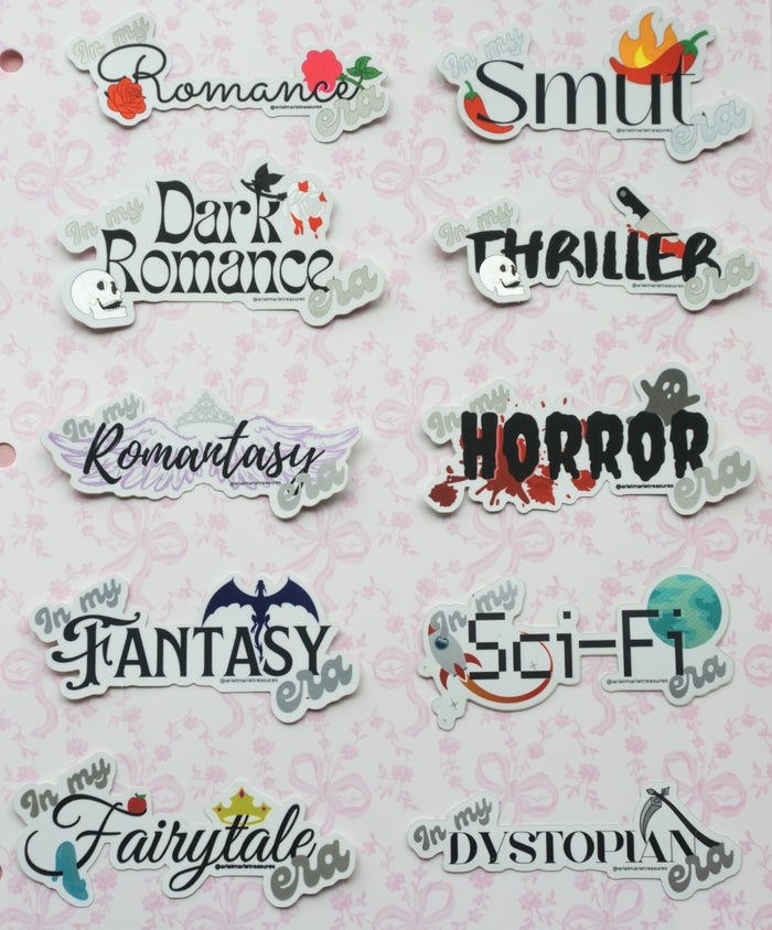 A sheet of die-cut sticker labels featuring various romance, thriller, fantasy, horror, and dystopian themes, arranged on a light pink patterned background.