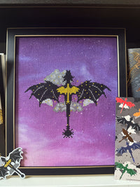 Fourth Wing-inspired cross stitch featuring black dragons, silver clouds, and a golden sword on purple fabric, displayed in a black and gold frame with coordinating dragon stickers.