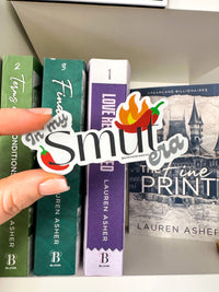 A hand holds a die-cut sticker that reads 'Smut era' with chili pepper illustrations over a row of Bloomsbury books, including 'Terms of Endearment', 'The Fine Print', and 'Love Redefined'.