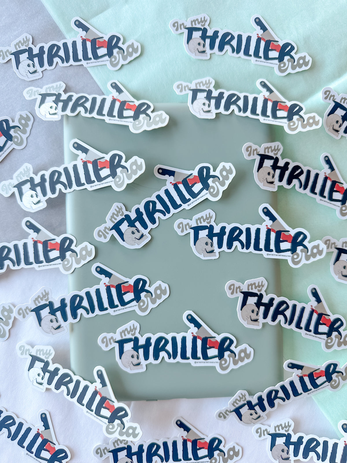 A collection of die-cut stickers featuring the phrase 'In my THRILLER bra' in stylized blue and red lettering with a small hand-drawn camera graphic, arranged on a mint green and white background.