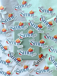 Multiple die-cut stickers with the phrase "in my Smut era" in white script and a red-orange flame chili pepper graphic, arranged on a mint green box over a white and pale green fabric background.
