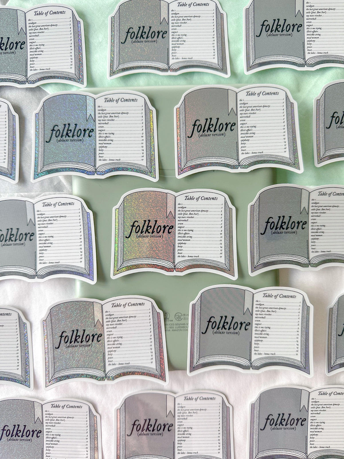 A repeating pattern of book-shaped table cards labeled 'folklore' and 'Table of Contents,' shown on a pale mint background.