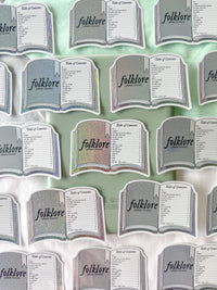 A repeating pattern of book-shaped table cards labeled 'folklore' and 'Table of Contents,' shown on a pale mint background.