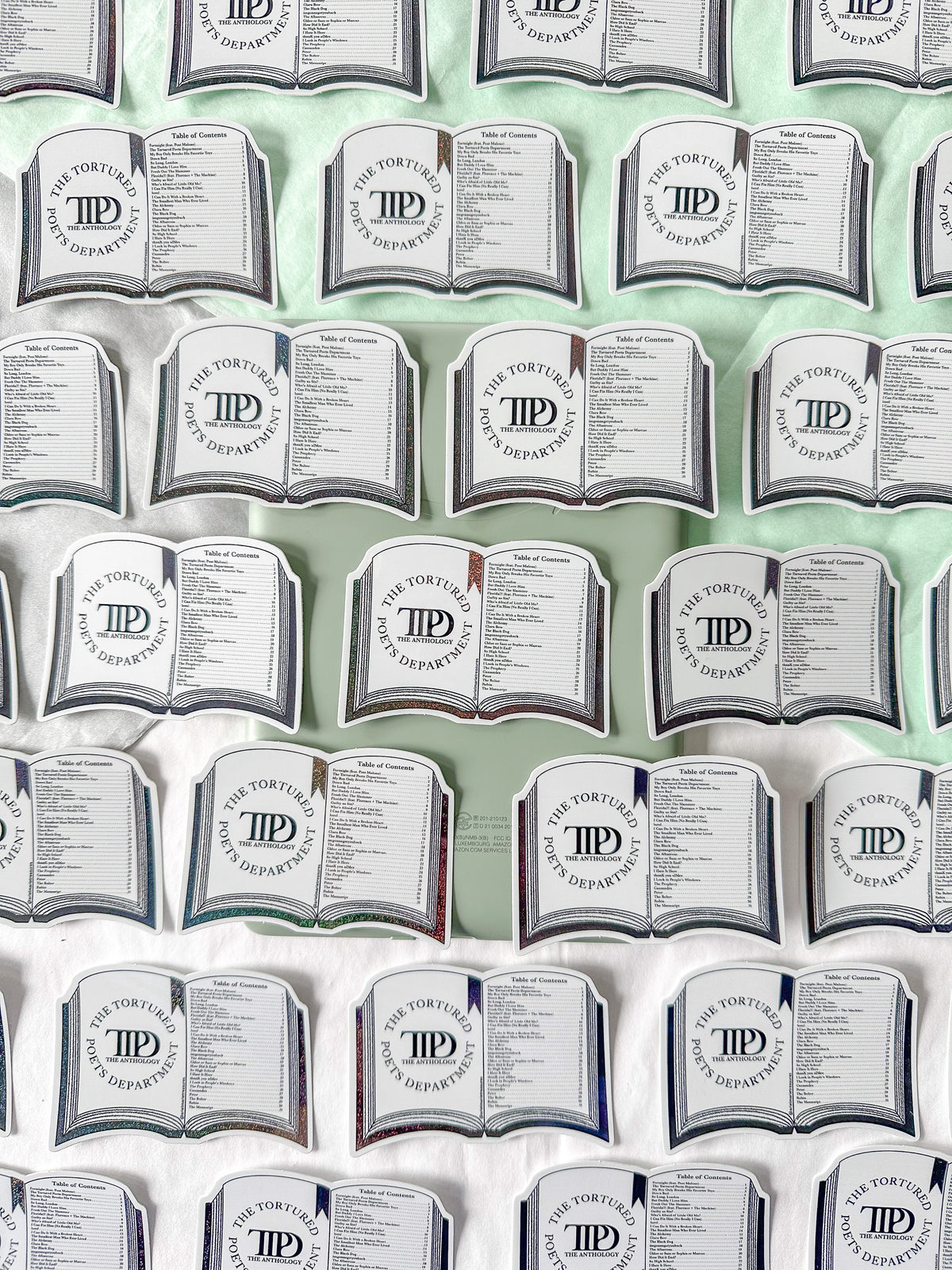 A repeating pattern of novelty pillows shaped like open books, each printed with the text 'The Tortoise and the Hare Department of Psychology' and a circular 'TPD' monogram, arranged on a white and pale green background.